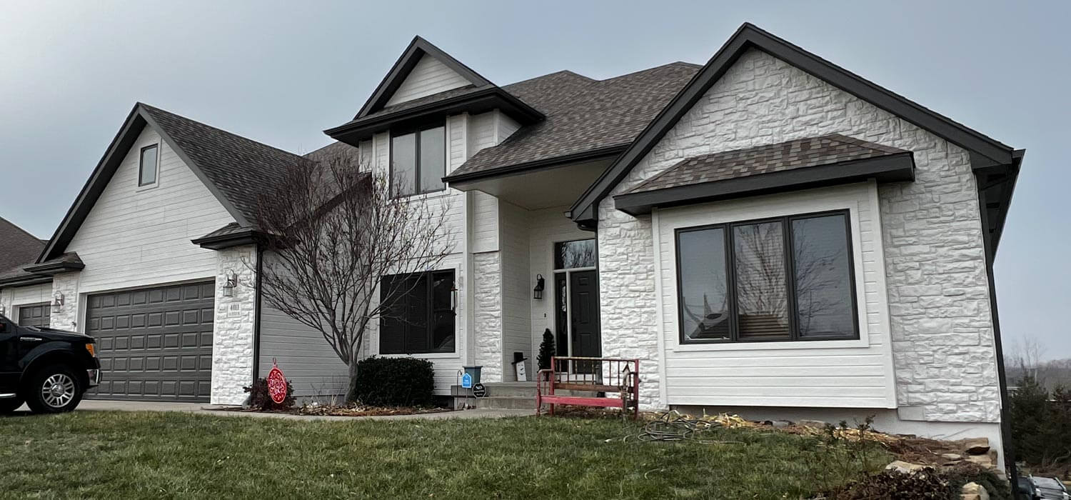 White stone and siding home with dark trim, refreshed by residential painters in Topeka, KS